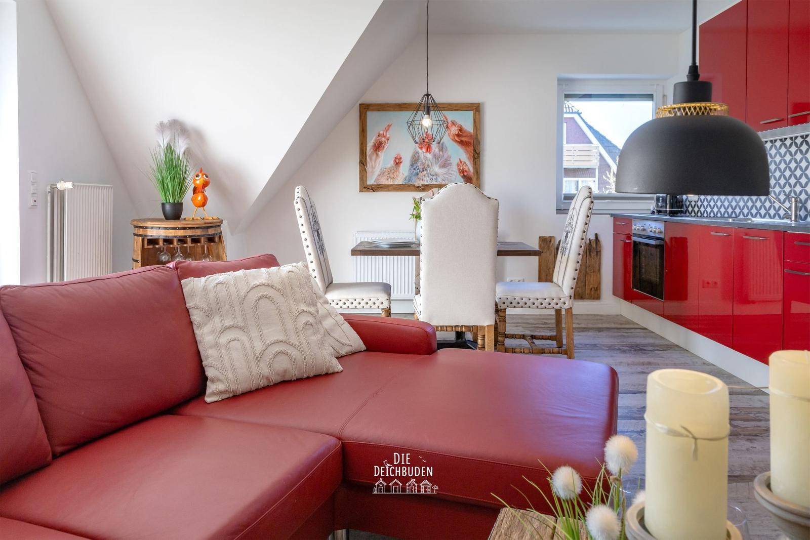 Roter Ledersofa im Wohnbereich mit Essbereich und roter Küchenzeile.