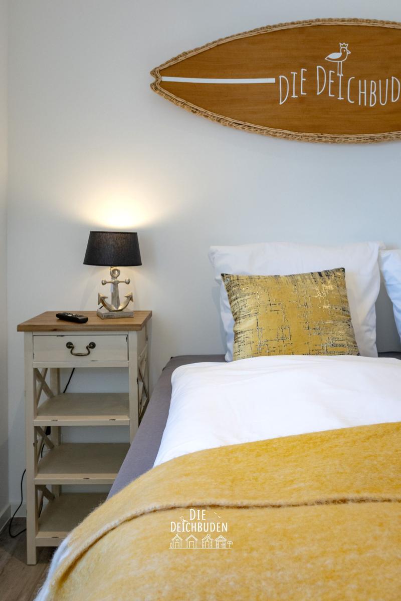 Schlafzimmer mit Bett, Nachttisch und Wanddekoration.