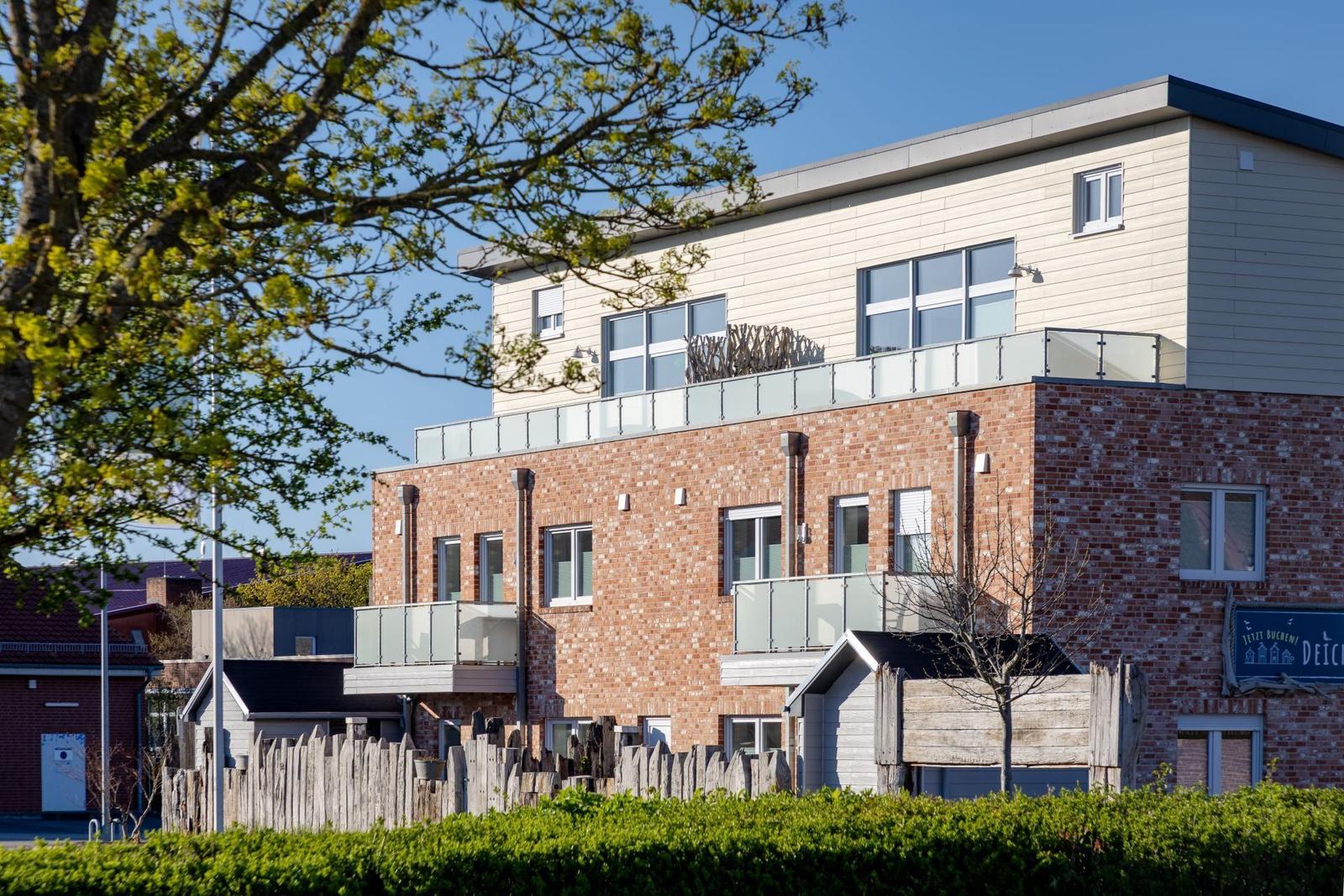 Moderne Ferienwohnung mit Balkonen und Glasgeländern. Roter Backsteinbau mit hellen Fassaden.