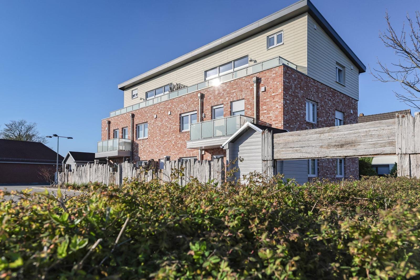 Modernes Mehrfamilienhaus mit Balkonen und Holzzaun