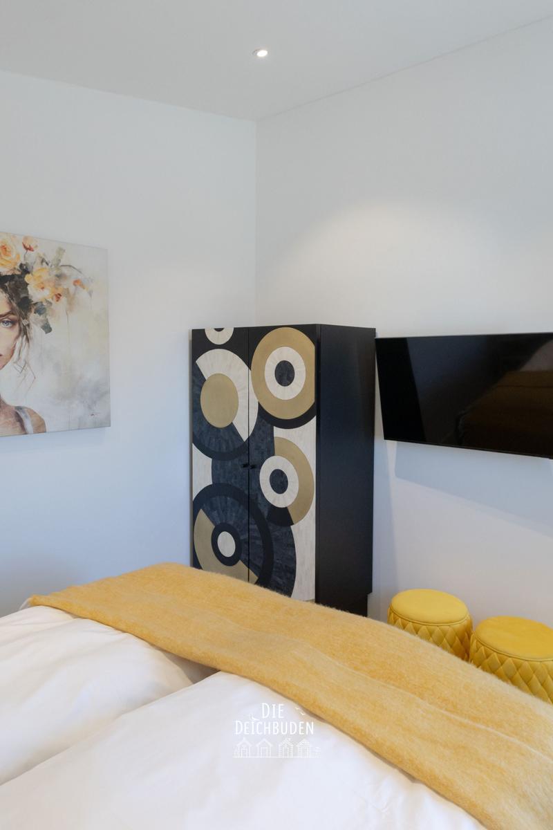 Schlafzimmer mit Bett, Wandbild, Kleiderschrank und TV.
