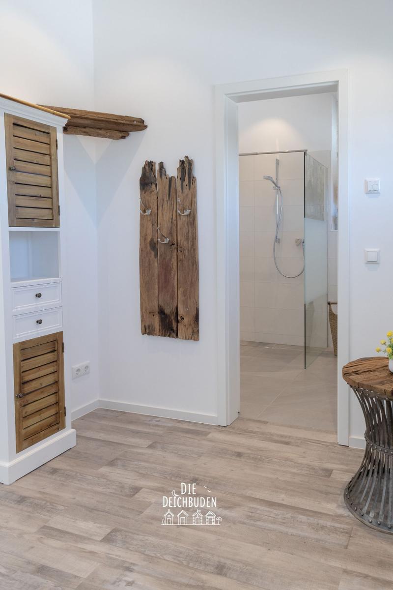 Flur mit Holzschrank, rustikalem Wandpaneel und Blick in die Dusche.
