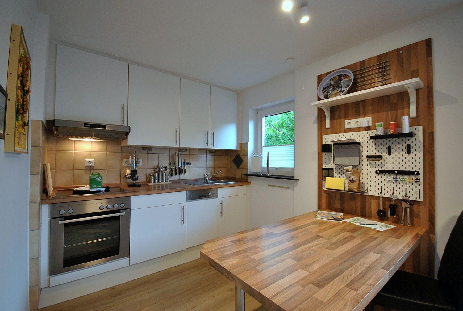 Küche mit Holzwerkzeugwand, Arbeitsplatte und Edelstahlgeräten.