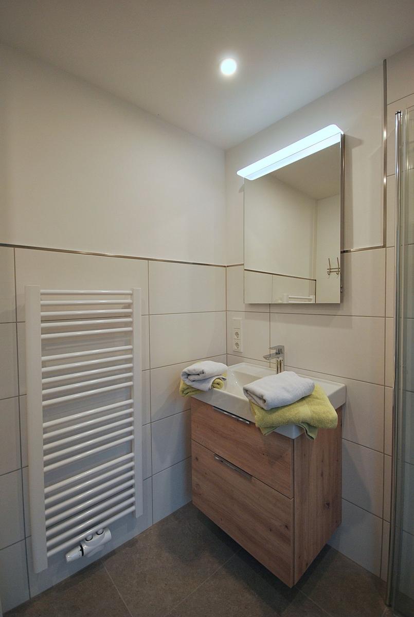 Badezimmer mit Waschbecken, Spiegelschrank und Heizkörper