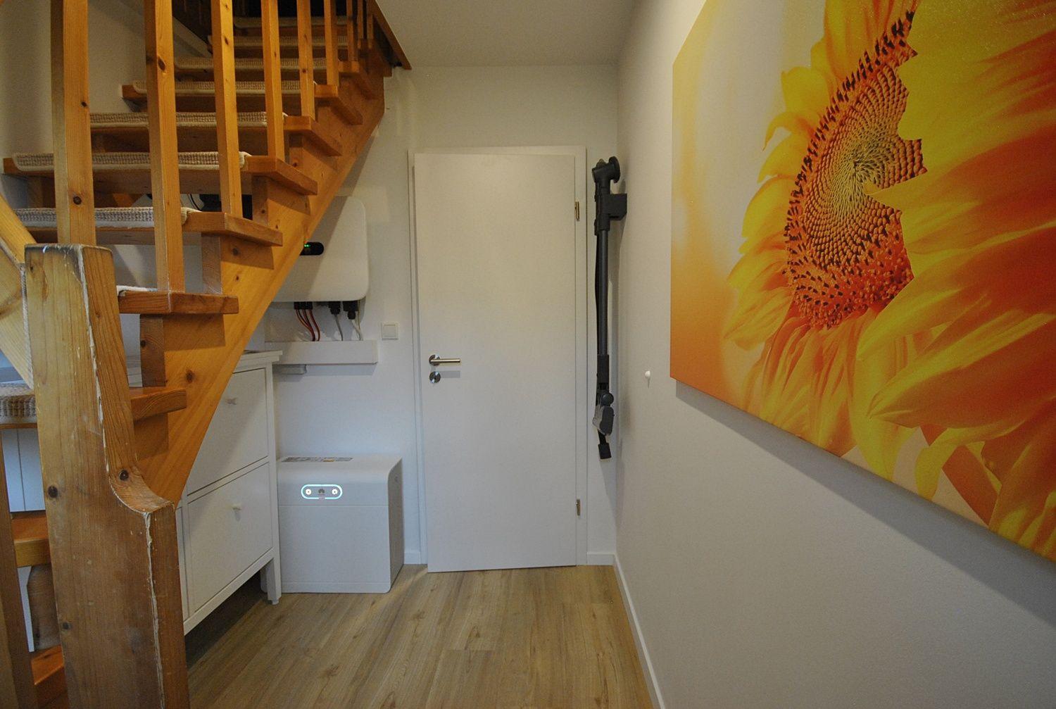 Halle mit Holztreppe, Wandbild Sonnenblume und Tür