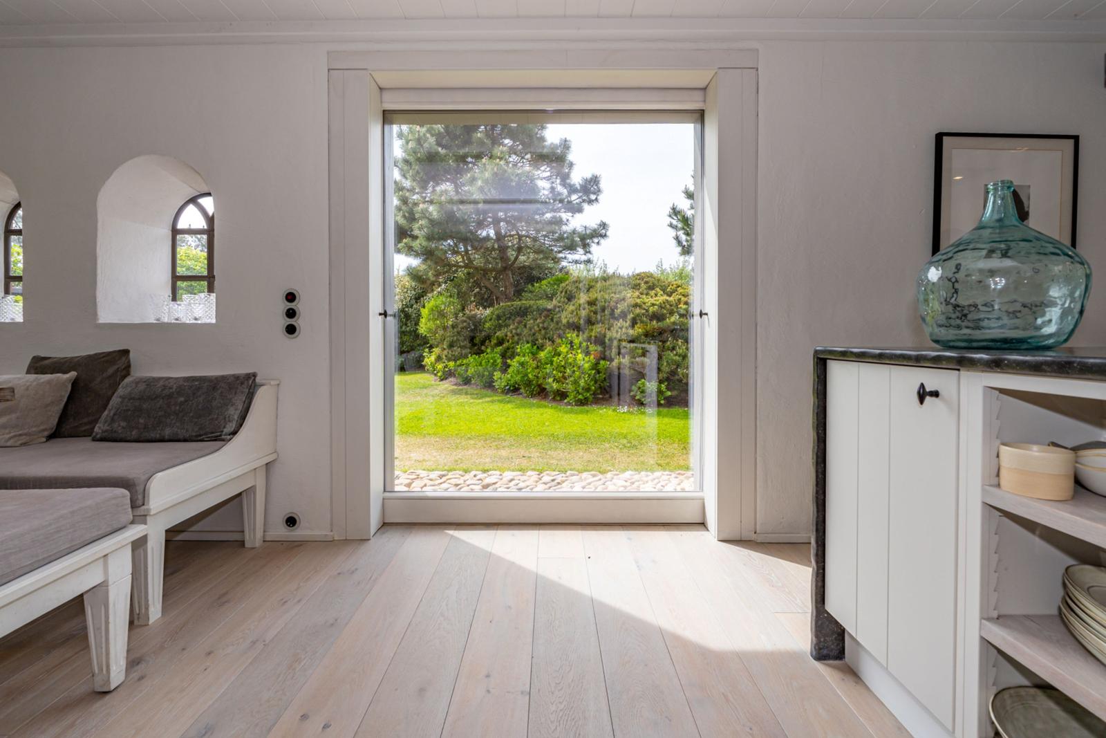 Raum mit Blick auf Garten. Fenster, Sofa, Schrank und Vasen sichtbar.