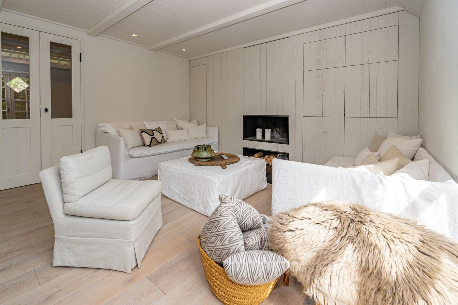 Wohnzimmer mit weißen Sofas, Kamin und Holzboden.