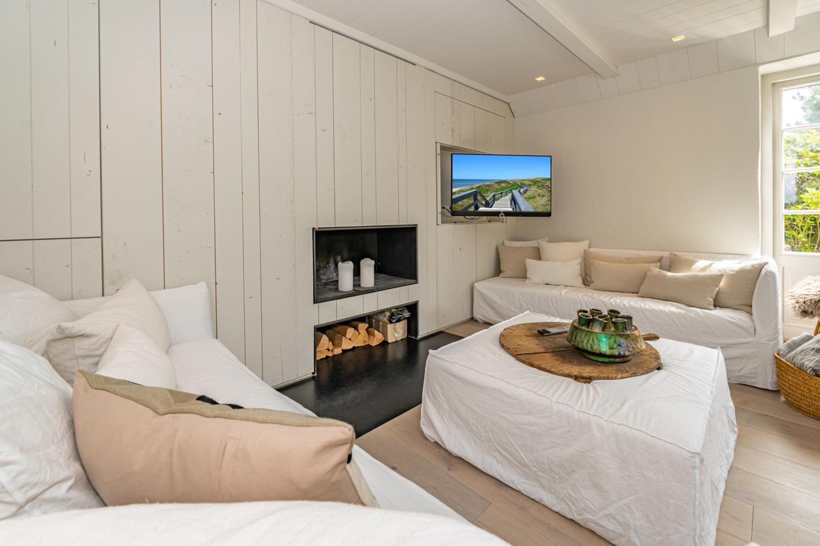 Wohnzimmer mit Sofa, Kamin und Fernseher an der Wand.