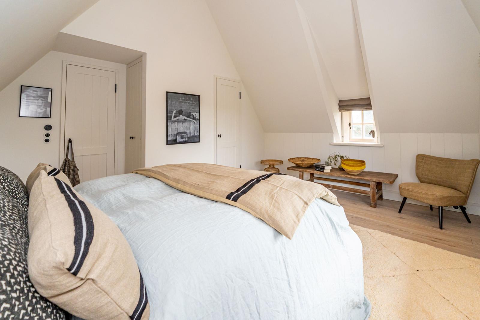 Schlafzimmer mit Dachschrägen, Bett, Stuhl und Fenster