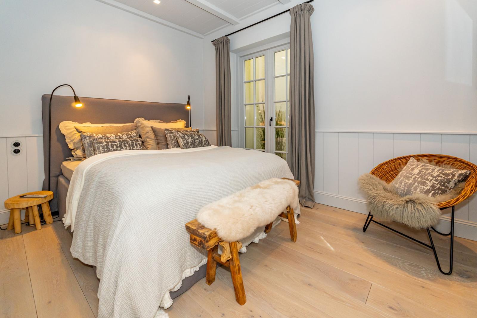 Schlafzimmer mit Bett, Holzbank, Stuhl und Fenster