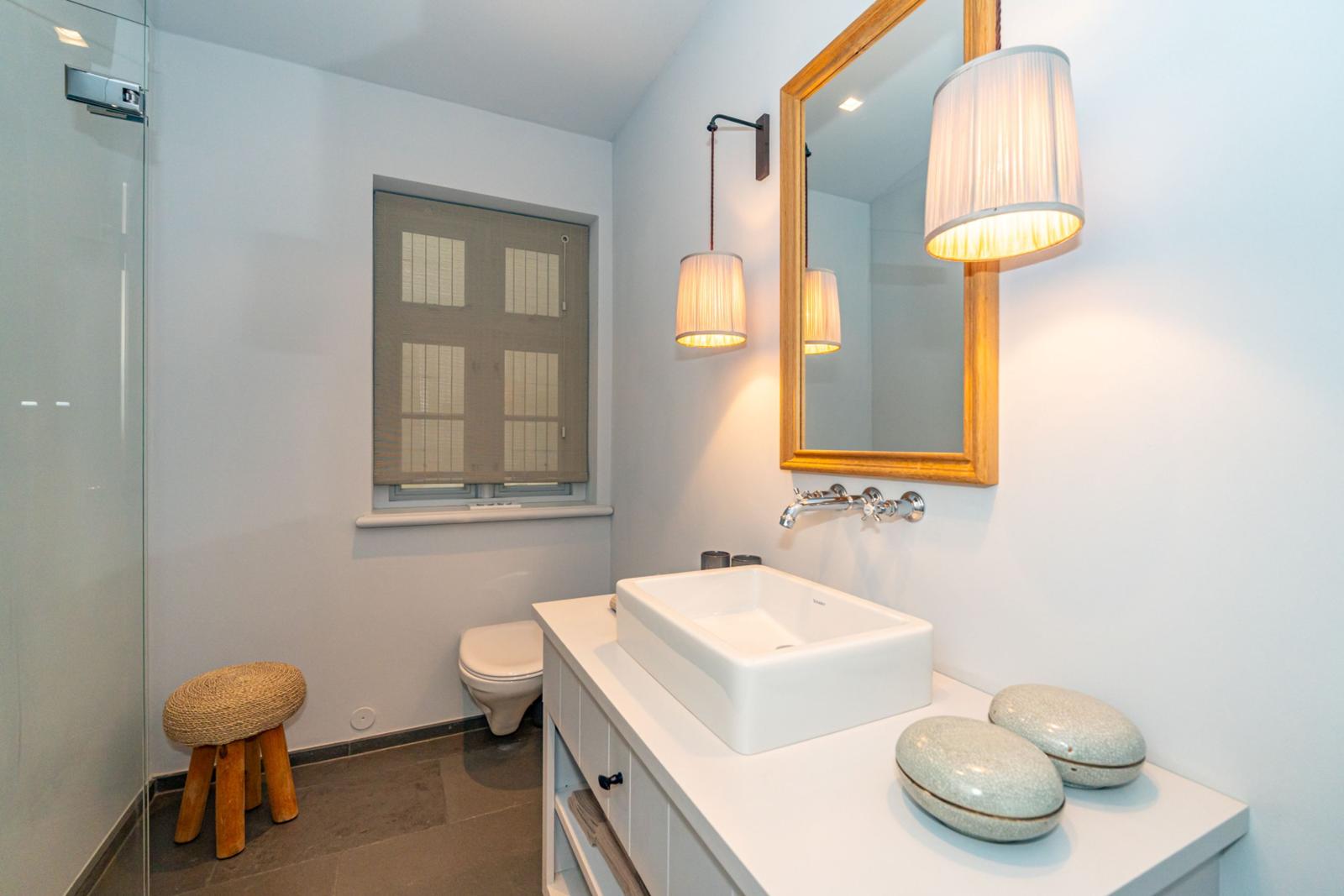 Badezimmer mit Waschtisch, Spiegel, Toilette und Dusche