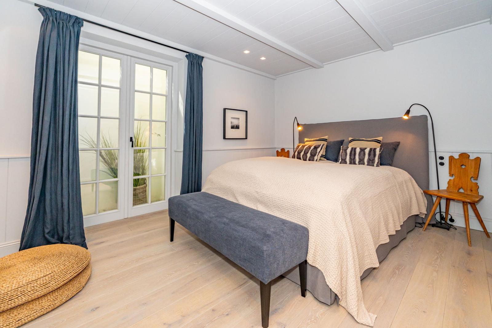 Schlafzimmer mit Bett, Fenster und Holzboden.