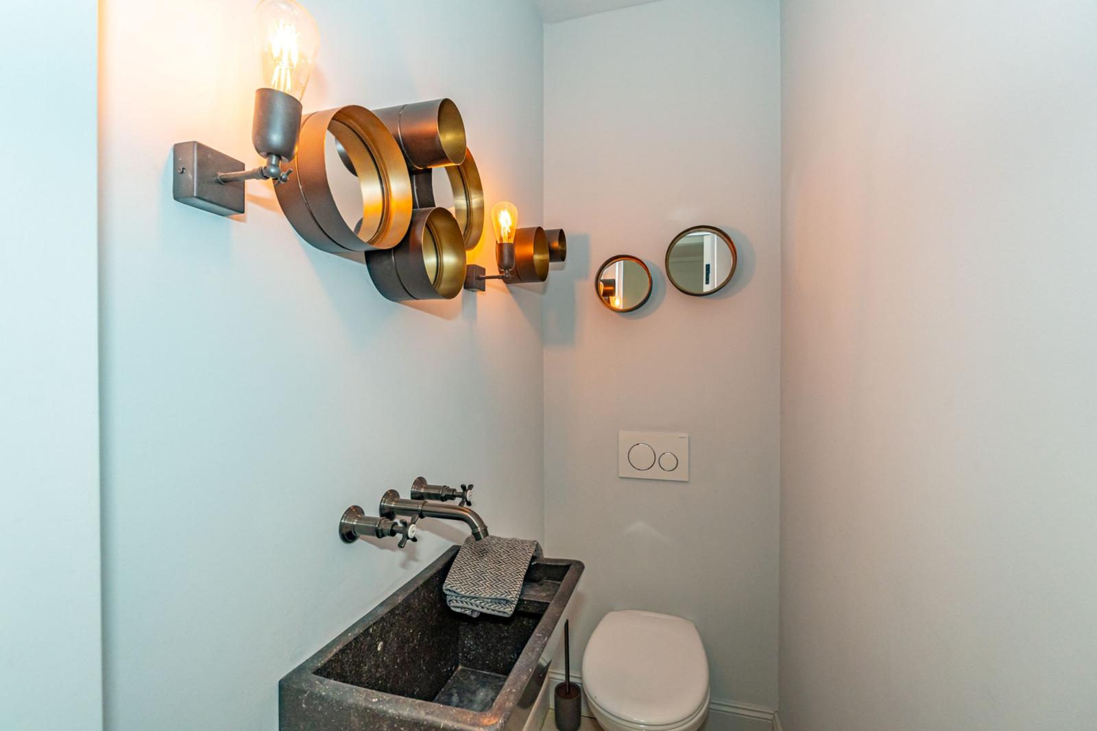 Badezimmer mit Waschbecken, Toilette und Wandbeleuchtung.