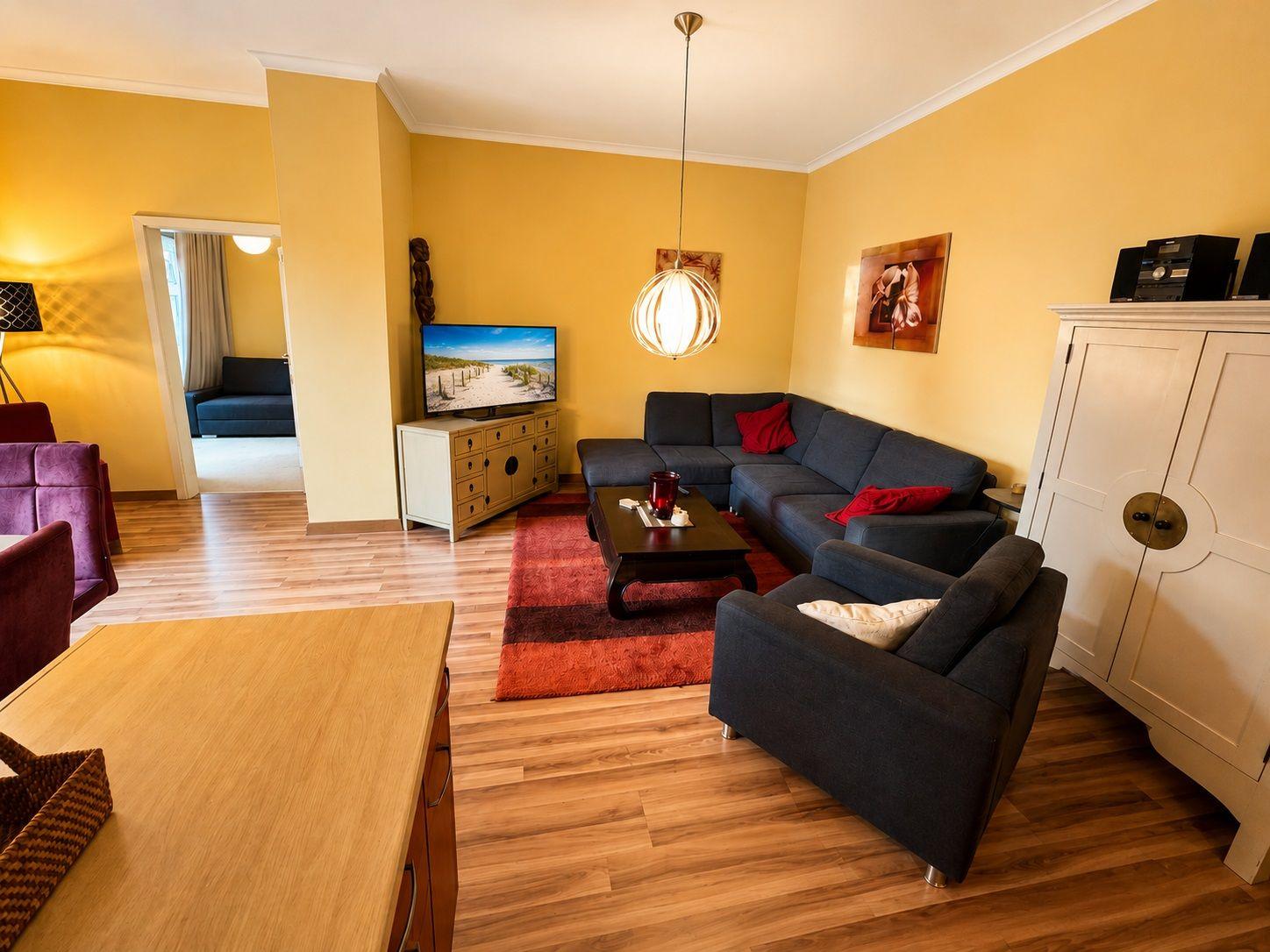 Wohnzimmer mit Sofa, Couchtisch und Fernseher auf Holzboden.