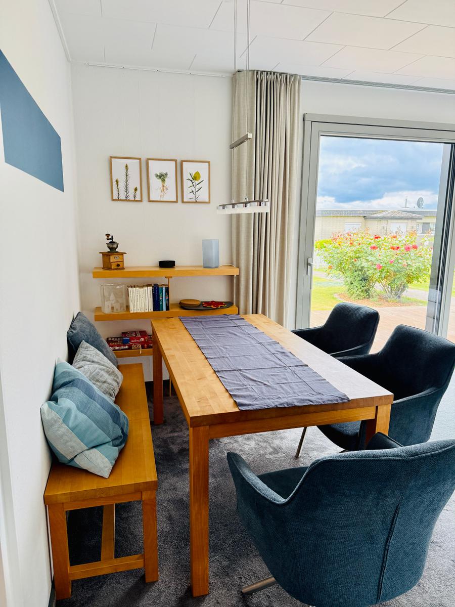 Essbereich mit Holztisch, dunkelblauen Stühlen und Blick auf Garten.