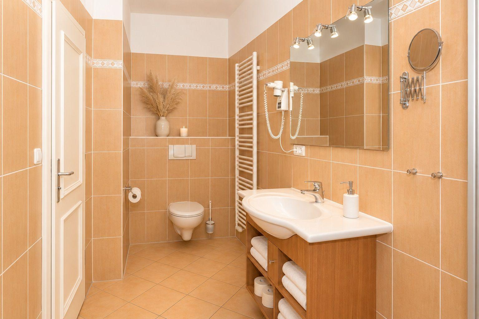 Badezimmer mit Waschbecken, Toilette und Handtuchhalter. Wandfliesen und Spiegel.