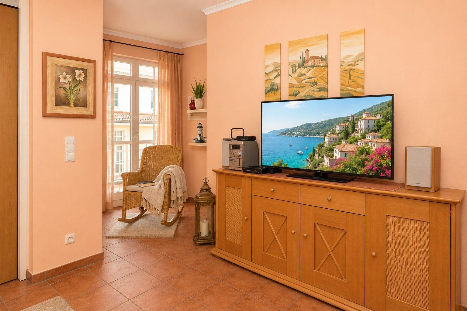 Ein Wohnzimmer mit Fernseher, Holzschrank und Schaukelstuhl. Wandbild und Fenster mit Blick.