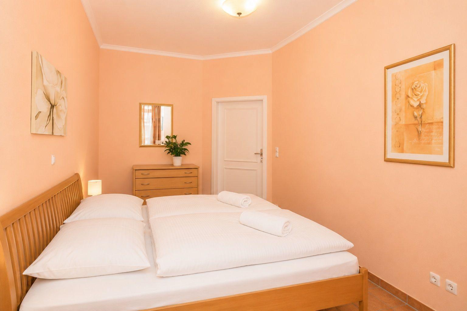 Schlafzimmer mit Bett, Schrank und Wandbildern