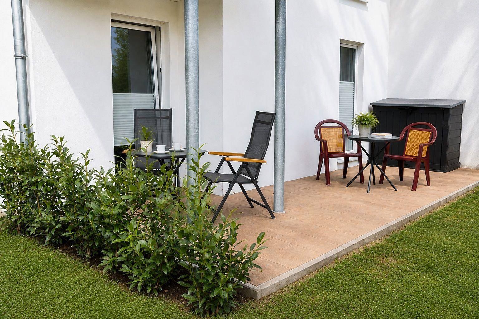Terrasse mit zwei Sitzgruppen, Pflanzen und Gartenbereich.