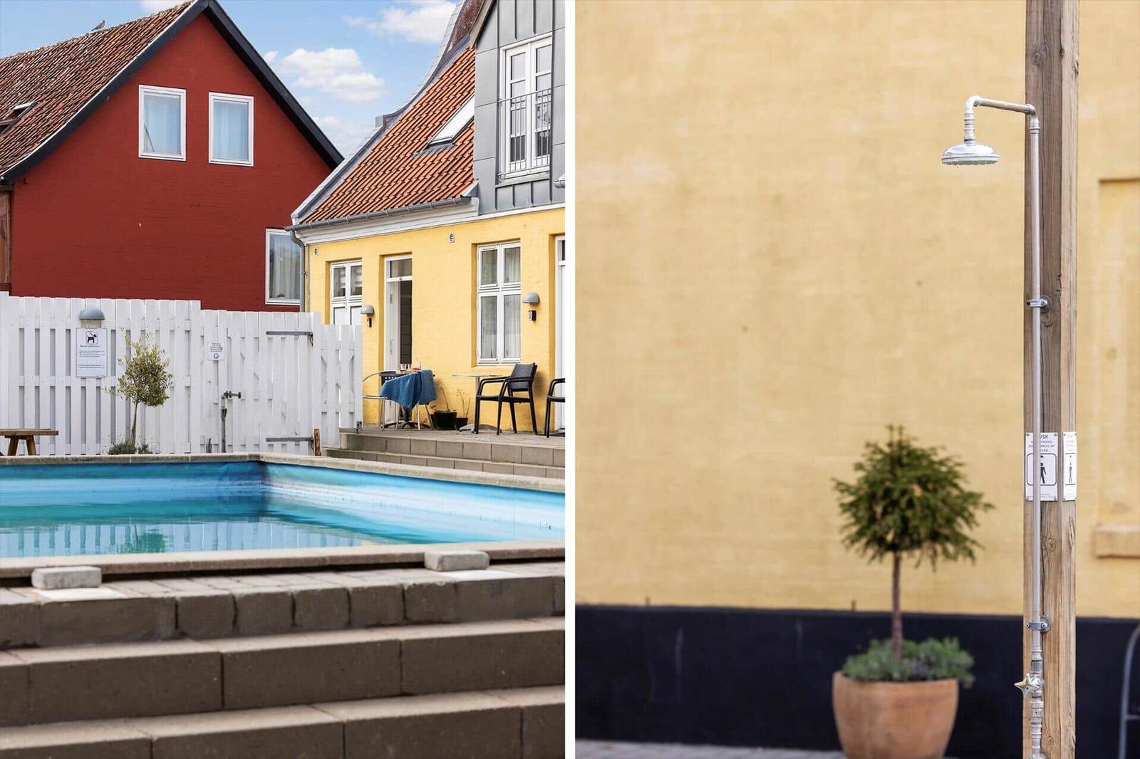 Pool area with terrace and outdoor shower near yellow house
