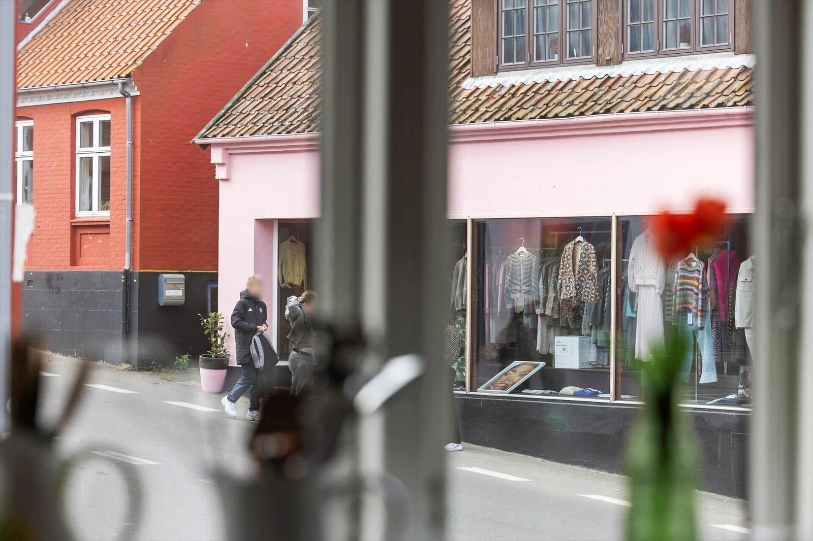 View from inside shows a street scene with a pink shop and a red house.