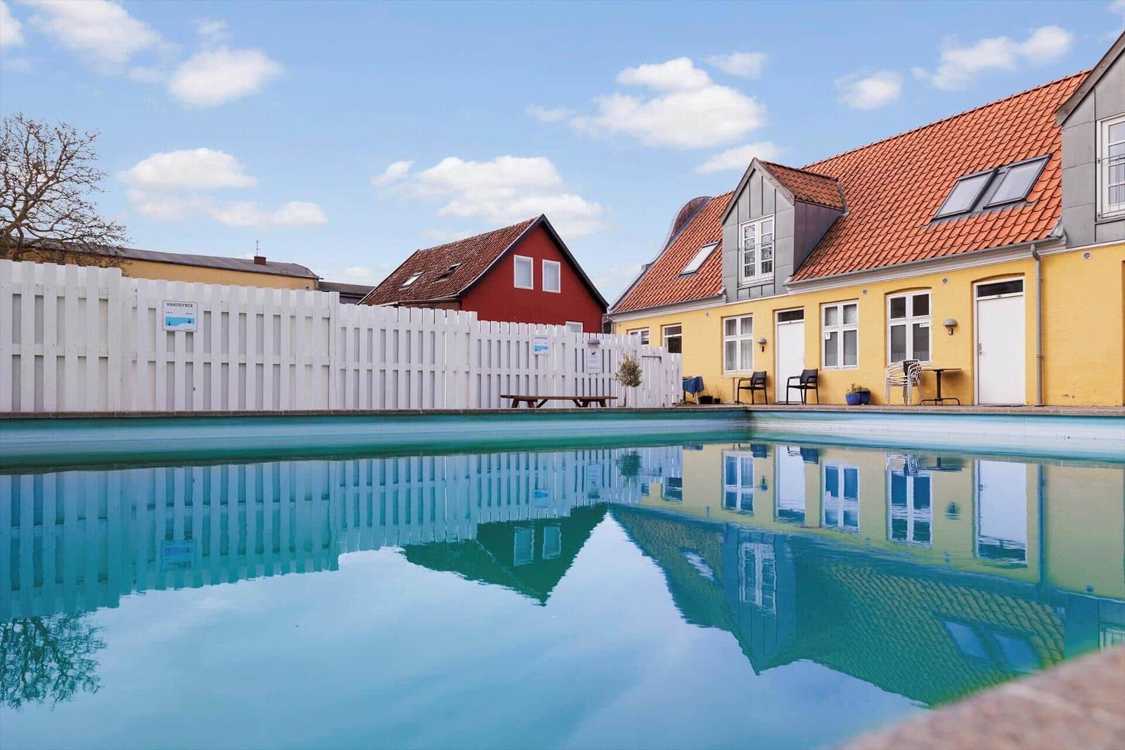 A pool with a view of yellow and red houses with red tiled roofs.