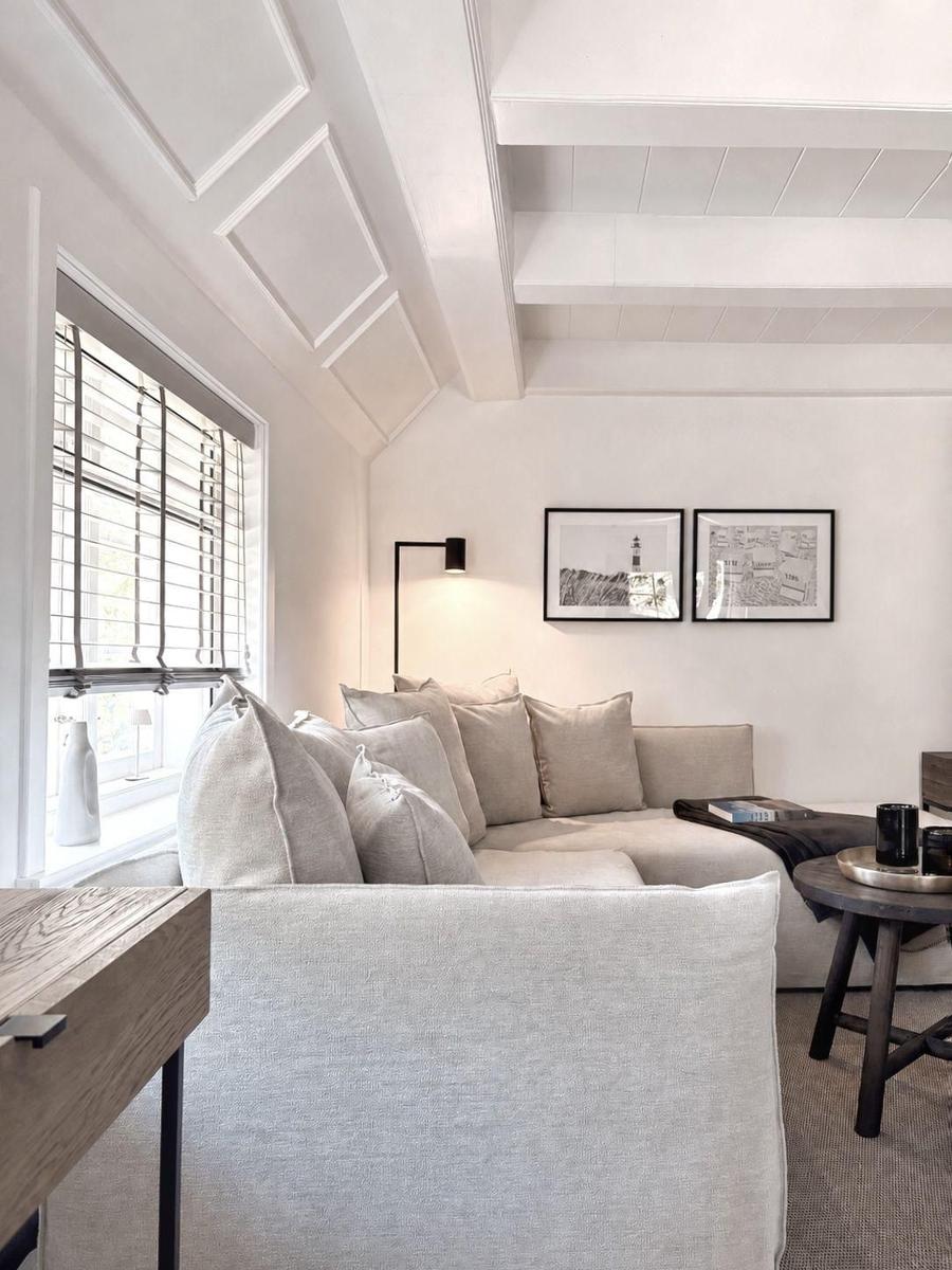 Ein Wohnzimmer mit Sofa, Fenster und Wandbildern.