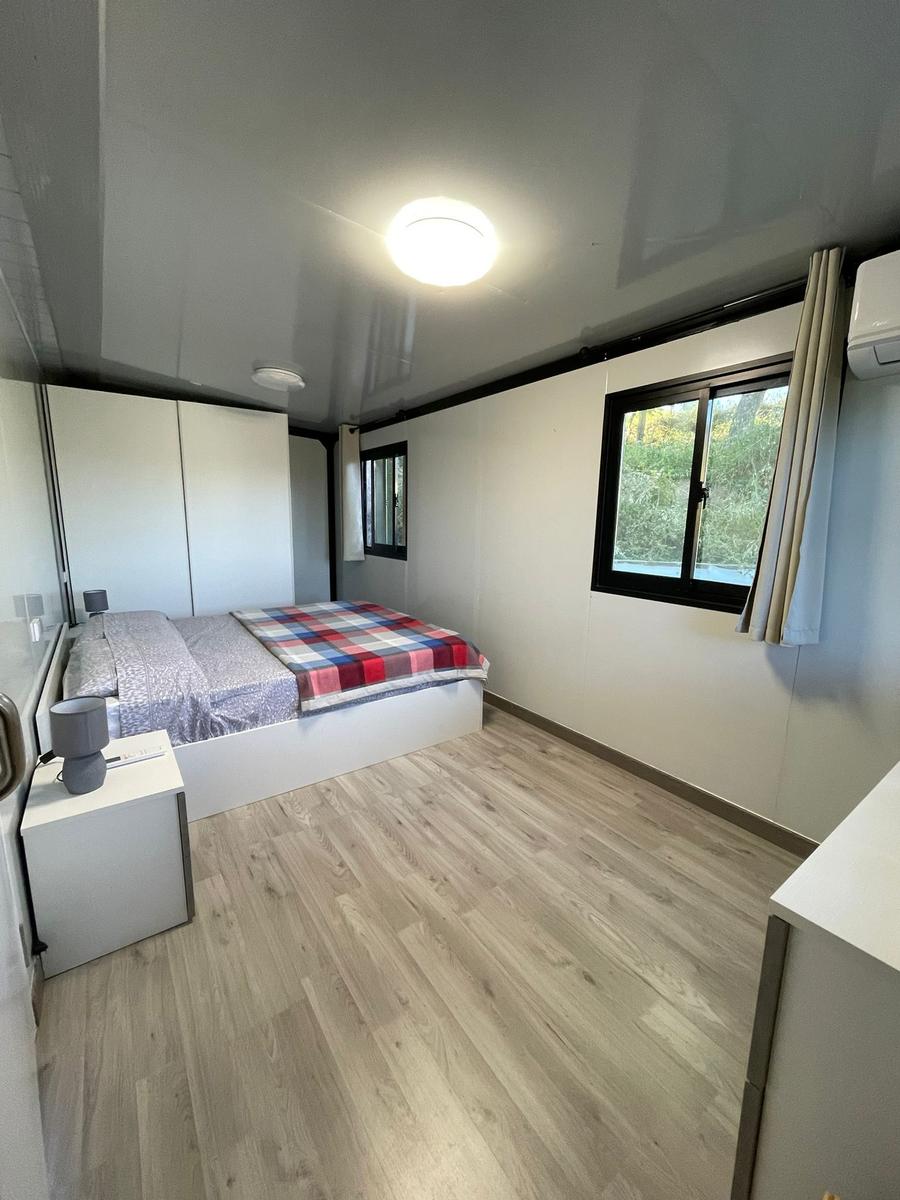 Bedroom with bed, wardrobe, and window. Wood floor and ceiling light.
