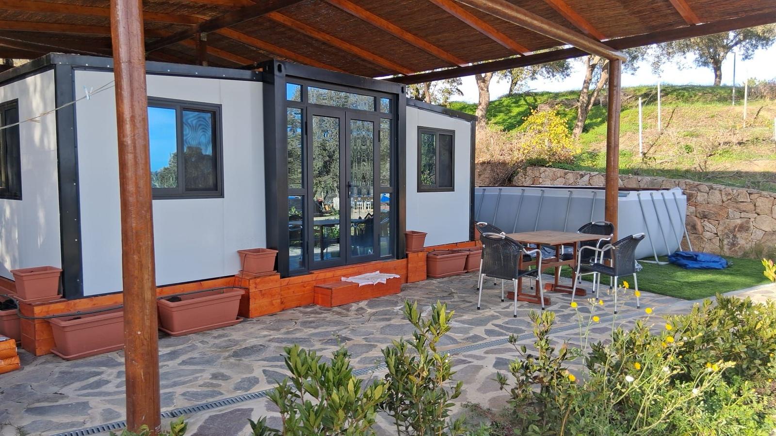 Patio with seating under roof, pool in background, plants and stone paving