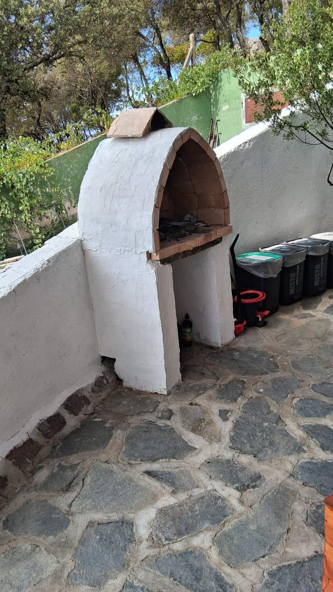 Outdoor area with stone paving and white oven. Background with trees and walls.