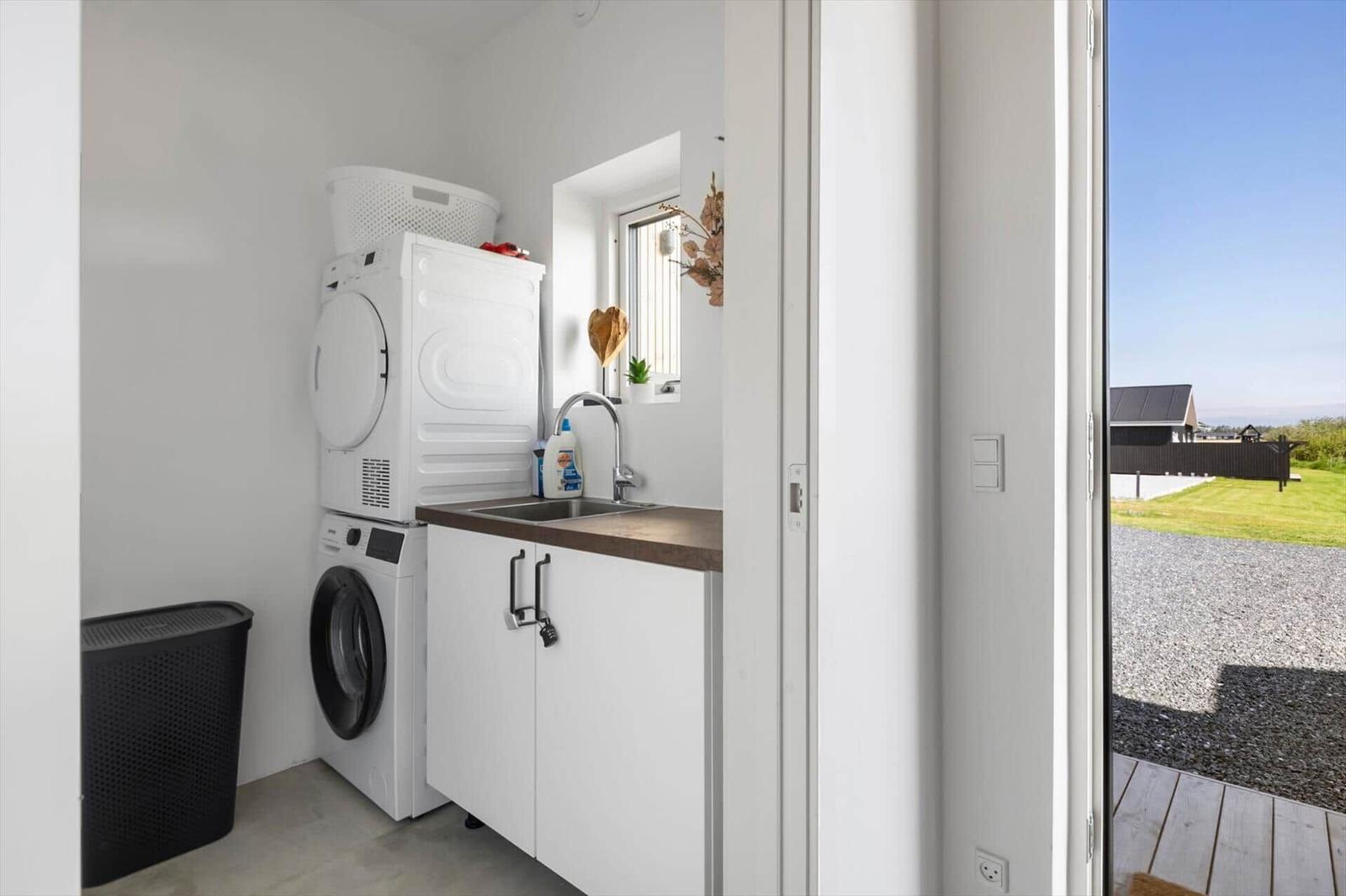 Wäscheservice mit Waschmaschine, Trockner und Waschbecken. Draußen ist ein gepflasterter Hof.
