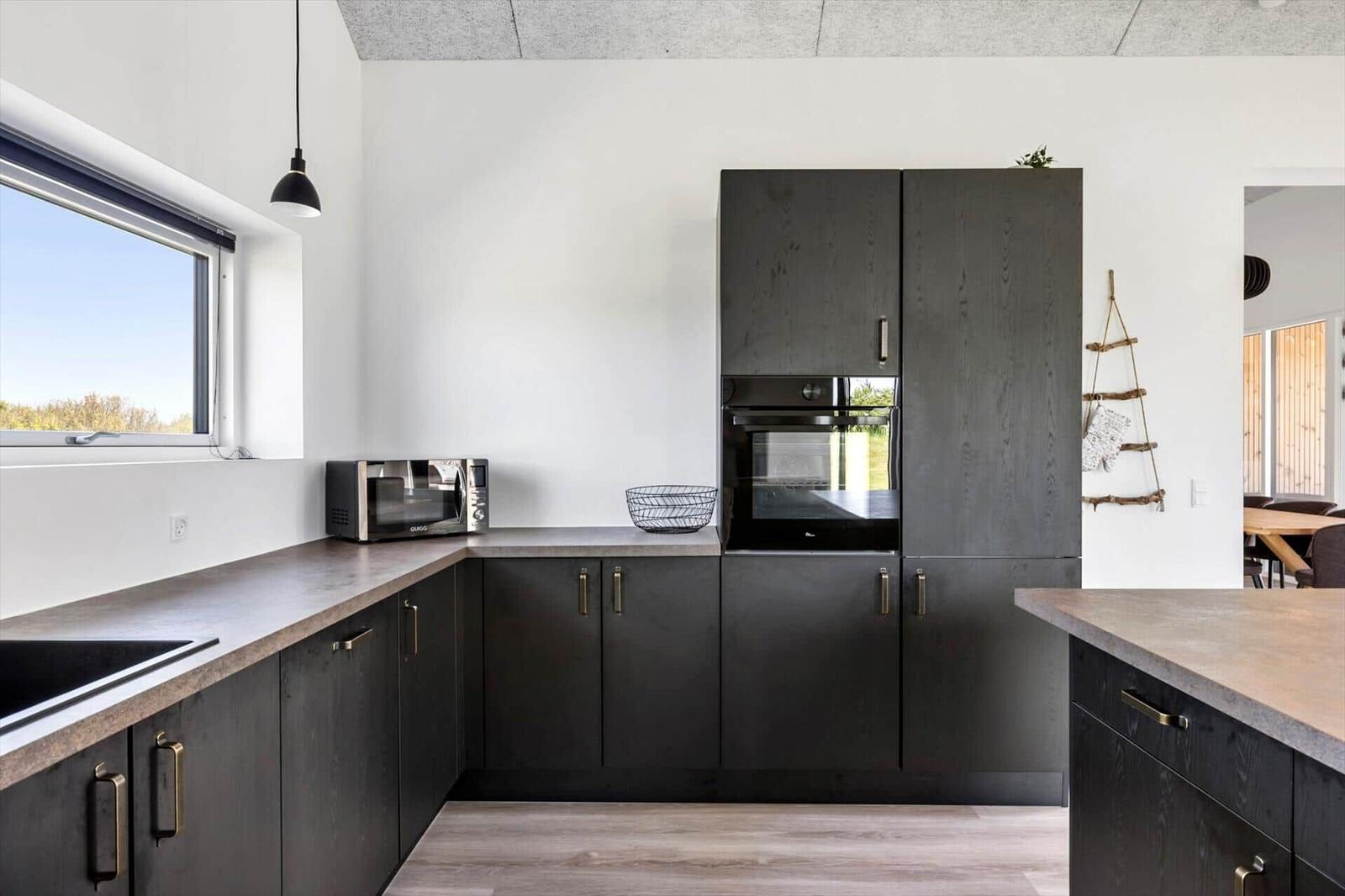 Moderne Küche mit dunklen Schränken, Arbeitsfläche und integriertem Ofen.