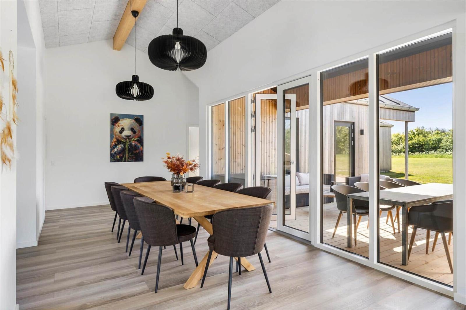 Esszimmer mit Holztisch, Stühlen und Glasfront zur Terrasse.
