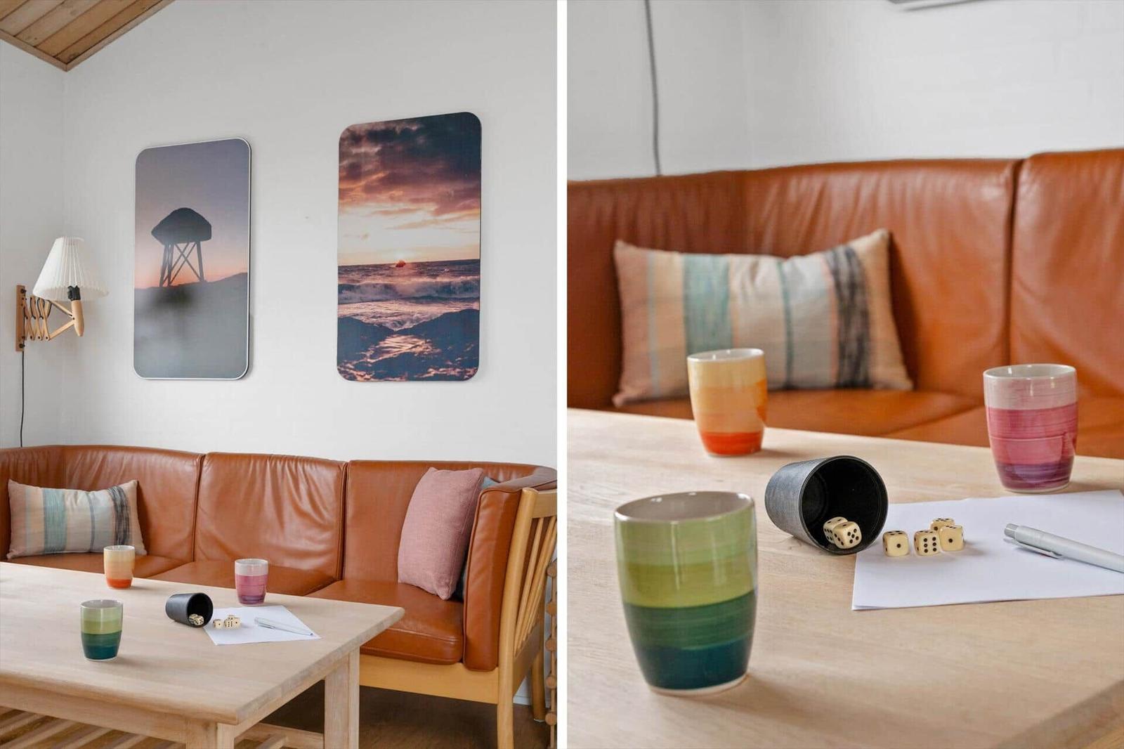 Living room with brown sofa, wooden table, and wall art. Cups and dice are on the table.