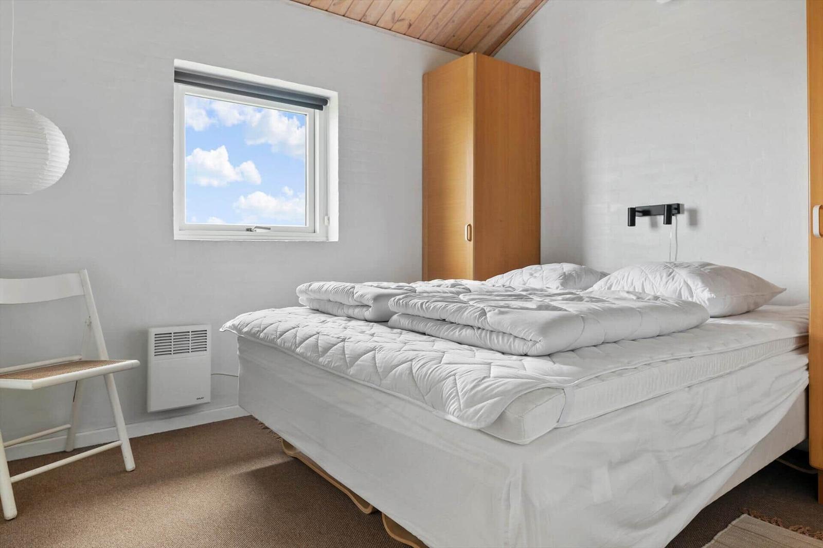 Bedroom with bed, wardrobe, and window with view of the sky.