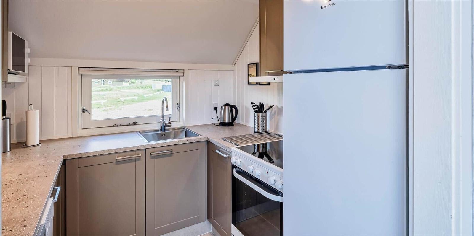 Küche mit Kühlschrank, Herd und Fenster zur Außenseite.