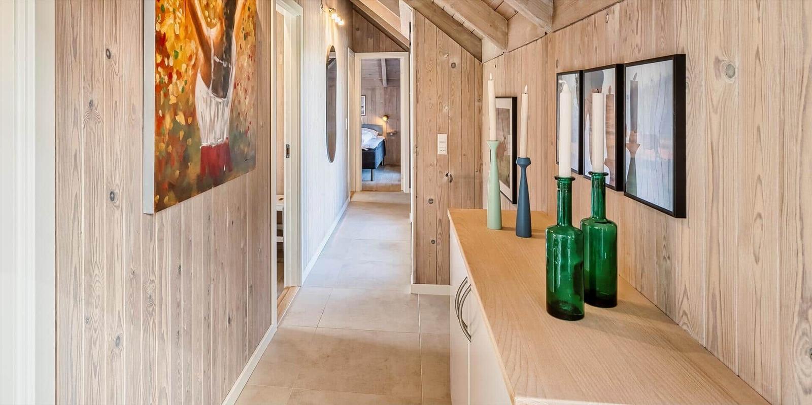 Flur mit Holzwand, Kunstwerken und grünen Glasflaschen auf einer Arbeitsplatte.