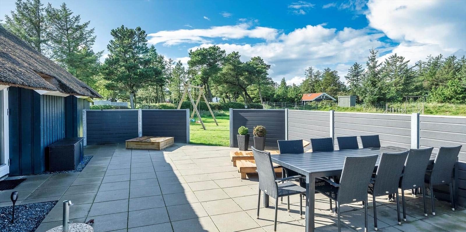 Terrasse mit Tisch, Stühlen und Spielplatz im Hintergrund.