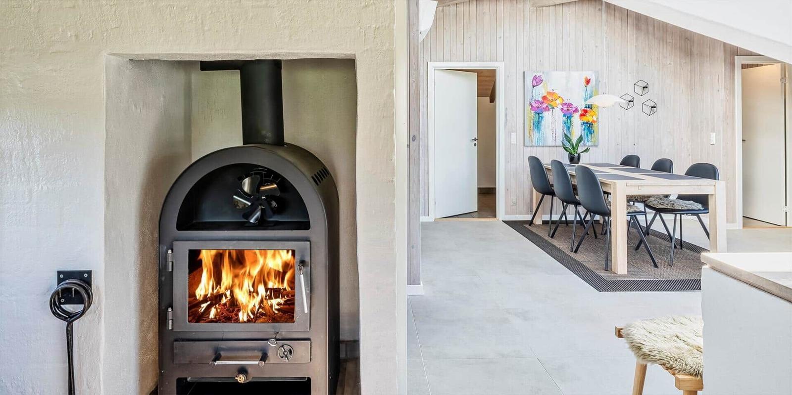 Ein Kaminofen mit brennendem Holz und ein Esszimmer mit Tisch und Stühlen.