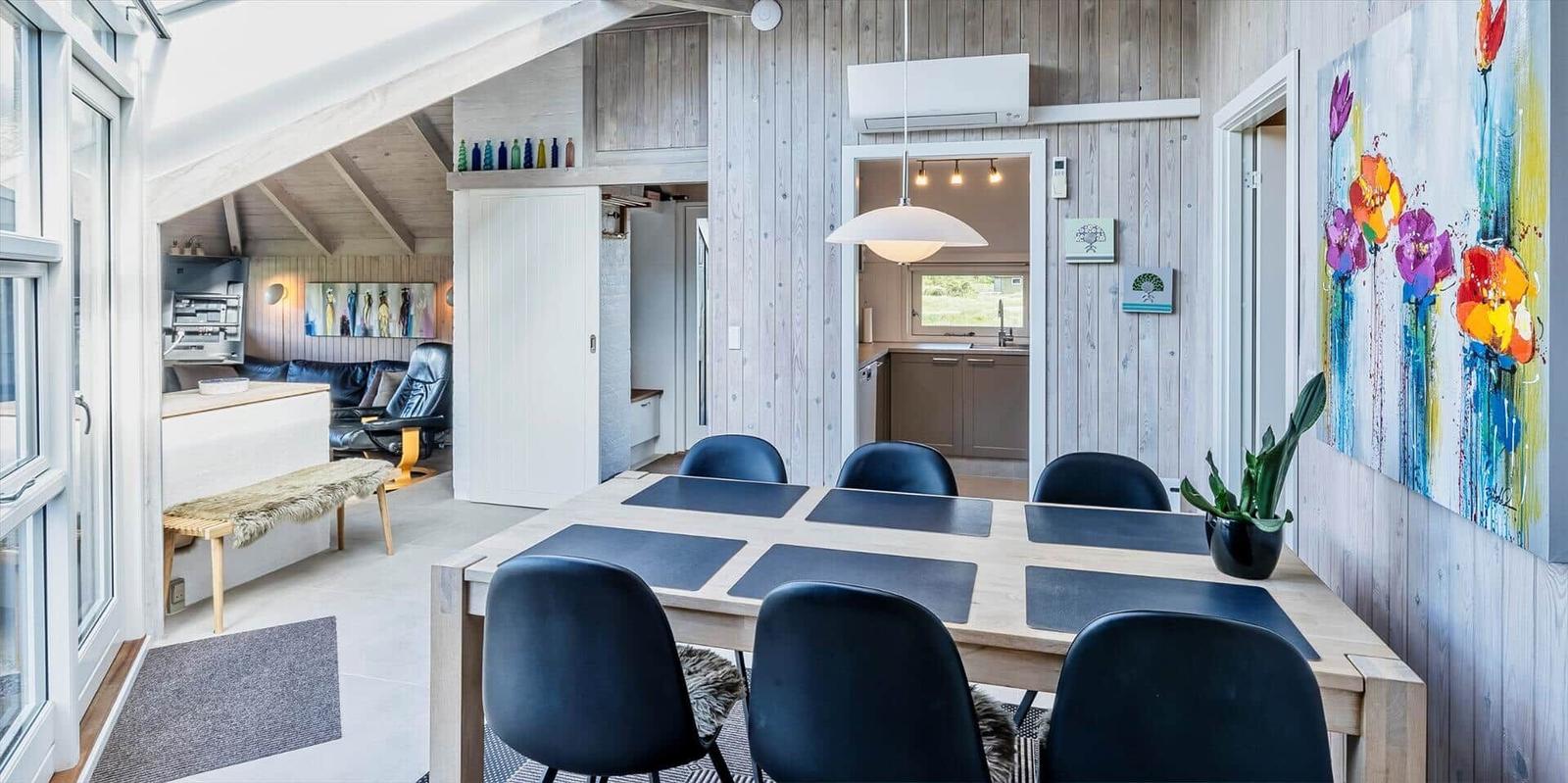 Essbereich mit Tisch und Stühlen, Wandbild und Blick in Küche und Wohnzimmer.