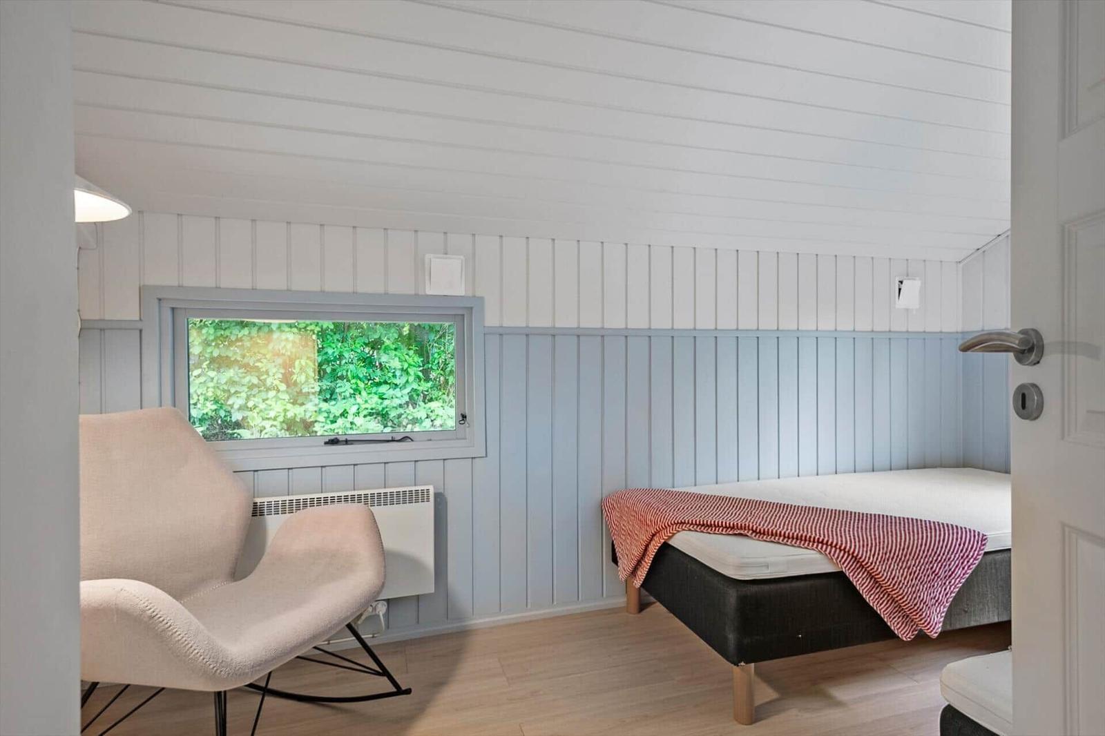 Schlafzimmer mit Bett, Stuhl und Fenster zum Blick in den Garten.