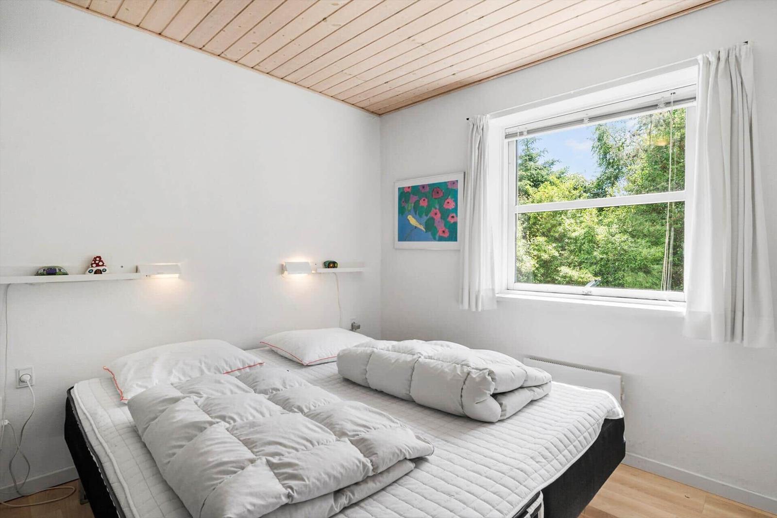 Ein Schlafzimmer mit Bett, Fenster und Wandbild.