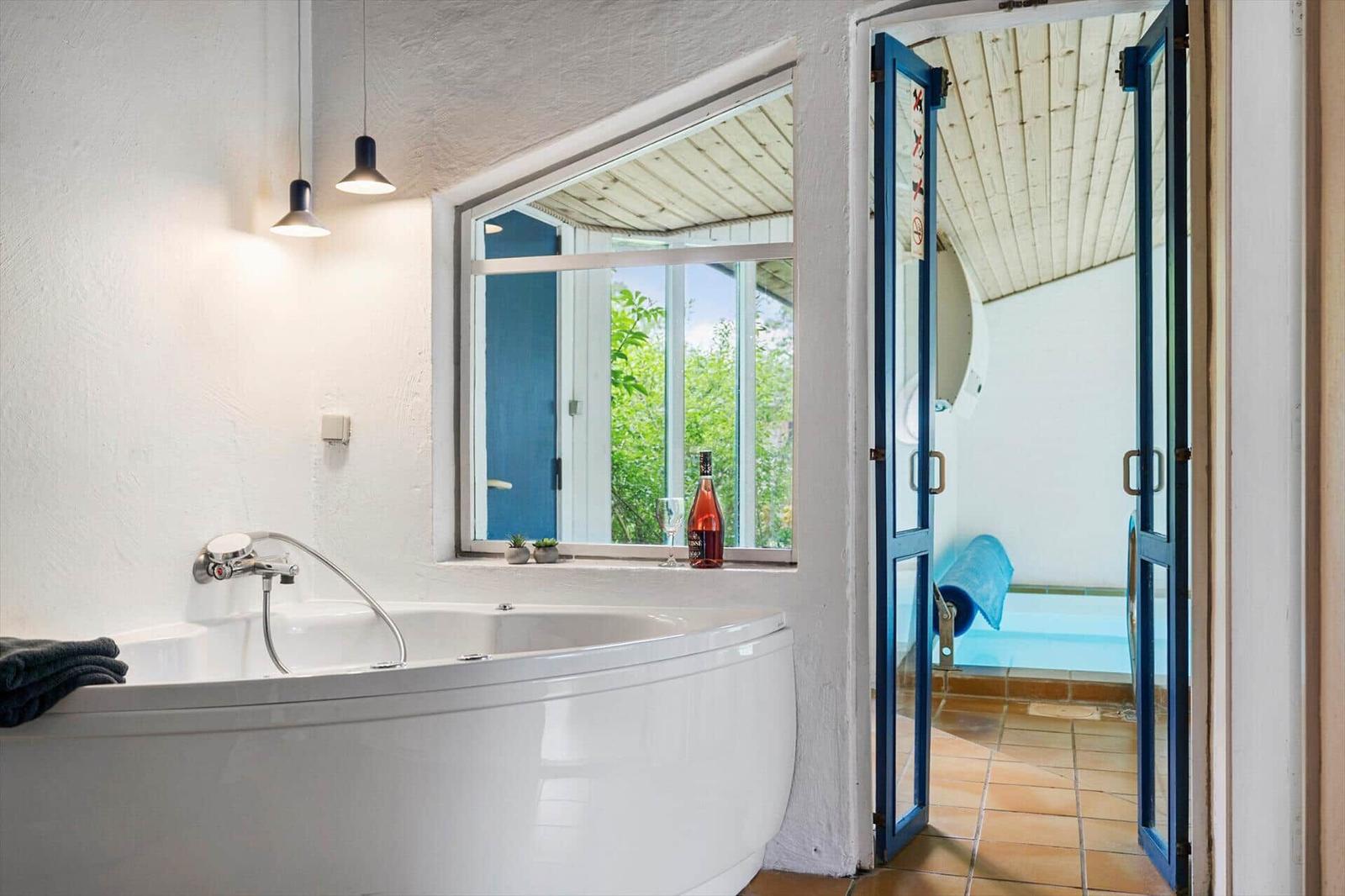 Bad mit Whirlpool, Fensterblick und Tür zum Außenbereich mit Pool.