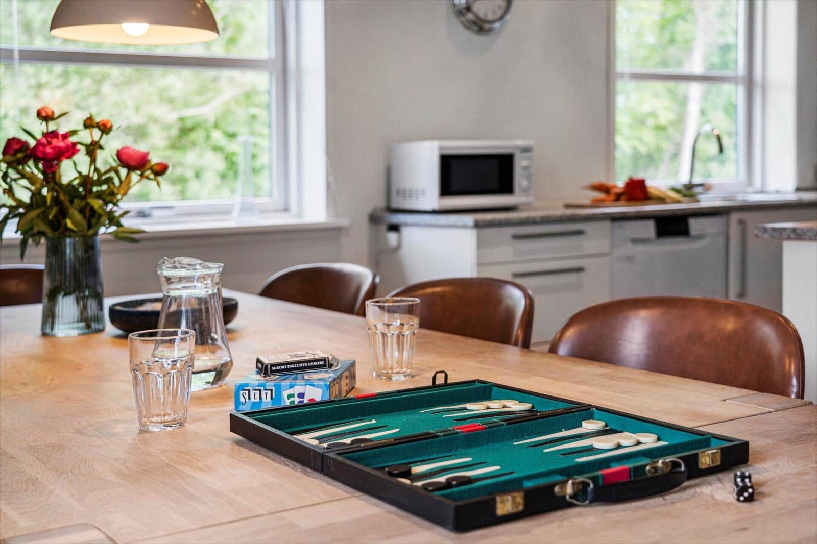 Esstisch mit Backgammon und Blumen vor Fenster