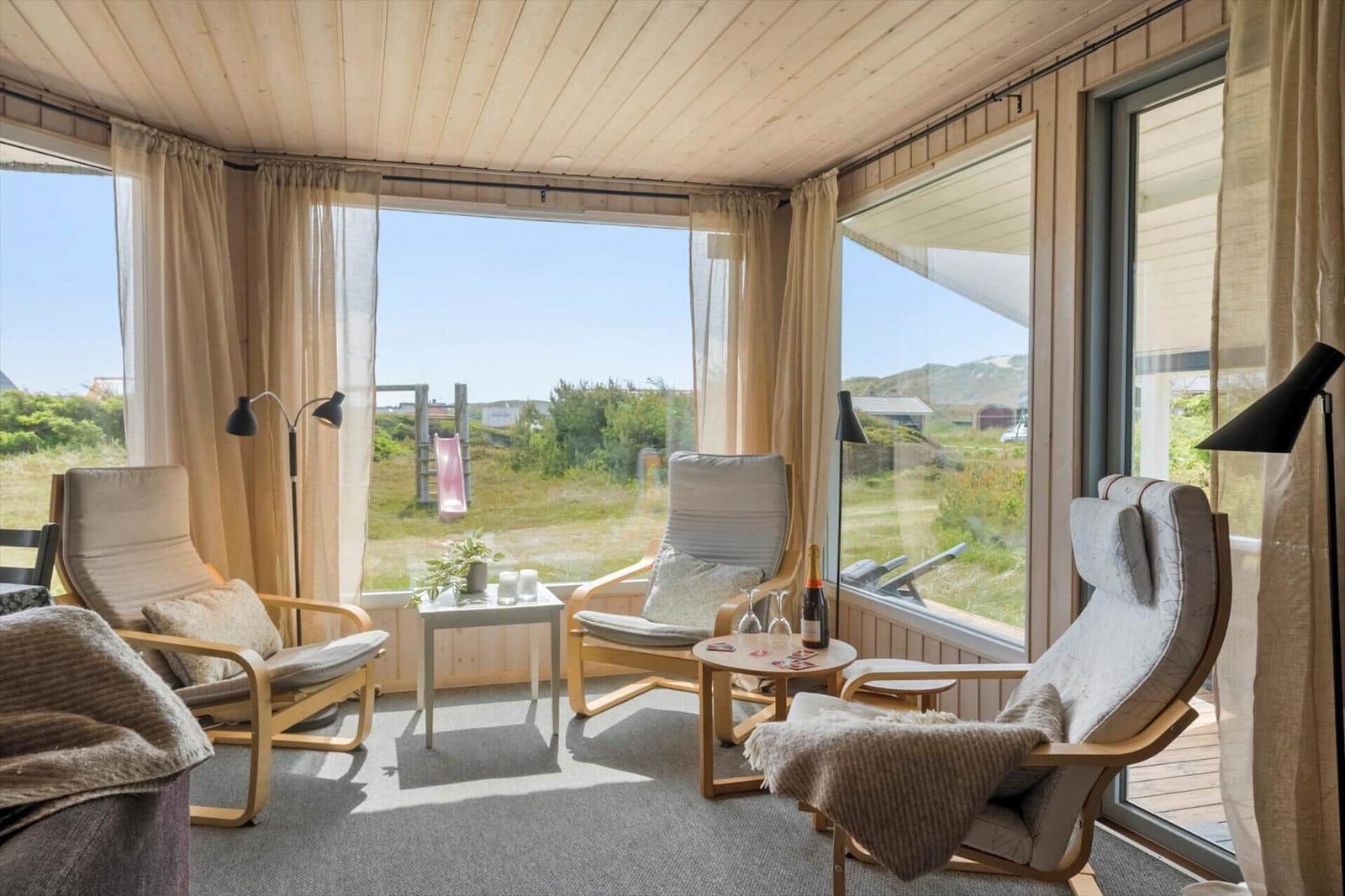 Raum mit drei Sesseln und großem Fensterblick auf grüne Landschaft.