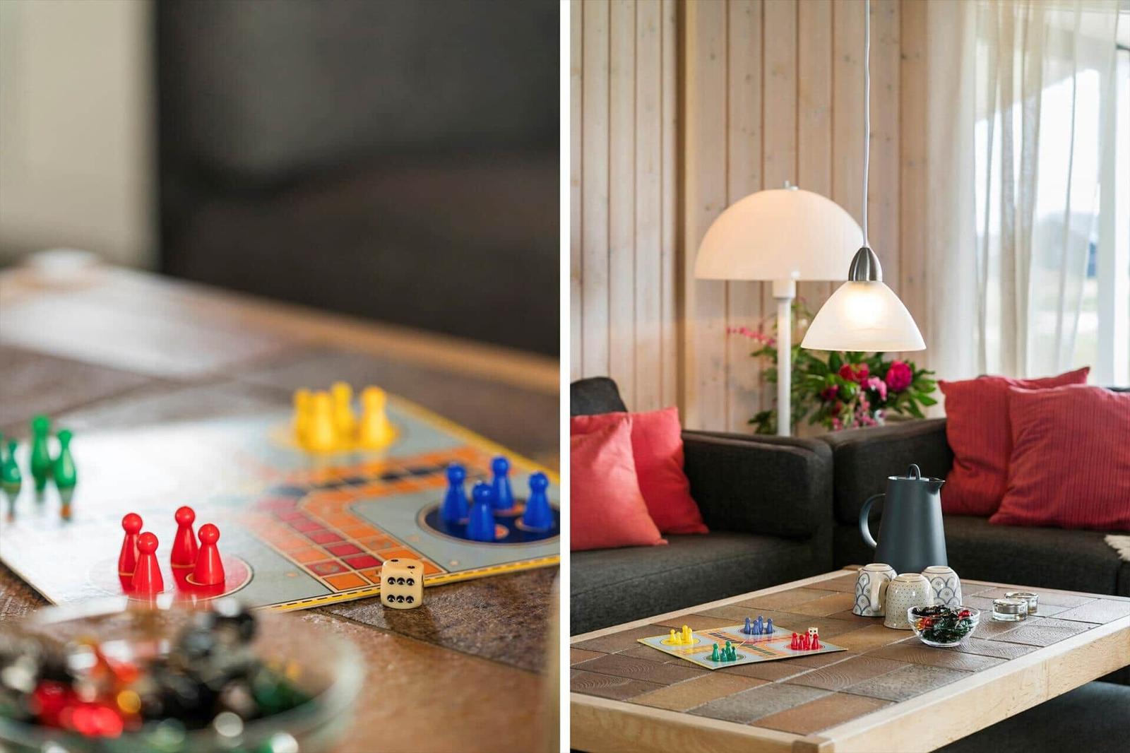 Tisch mit Brettspiel und Spielzeugfiguren. Sofa mit Kissen und Stehlampe.