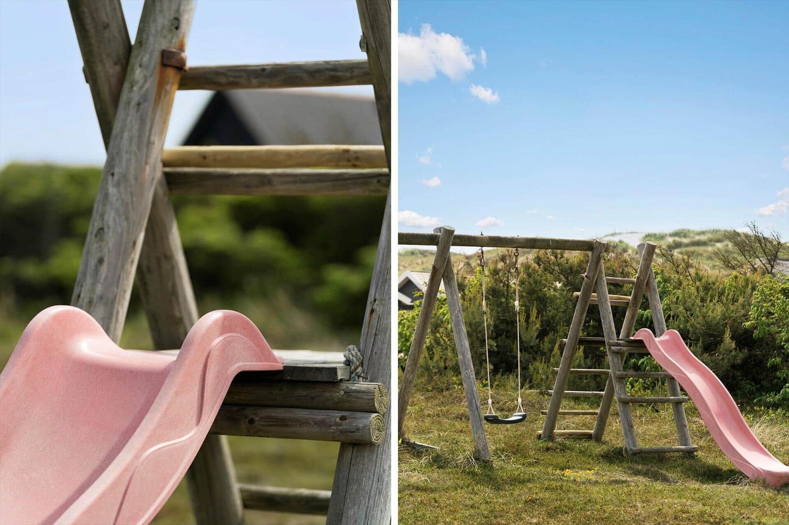 Holzspielplatz mit pinker Rutsche und Schaukel im Gras.