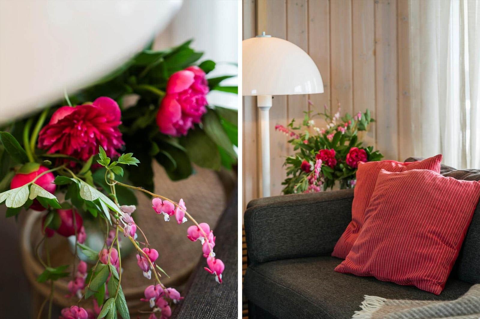 Ein Sofa mit Kissen und eine Stehlampe neben Blumenstrauß.