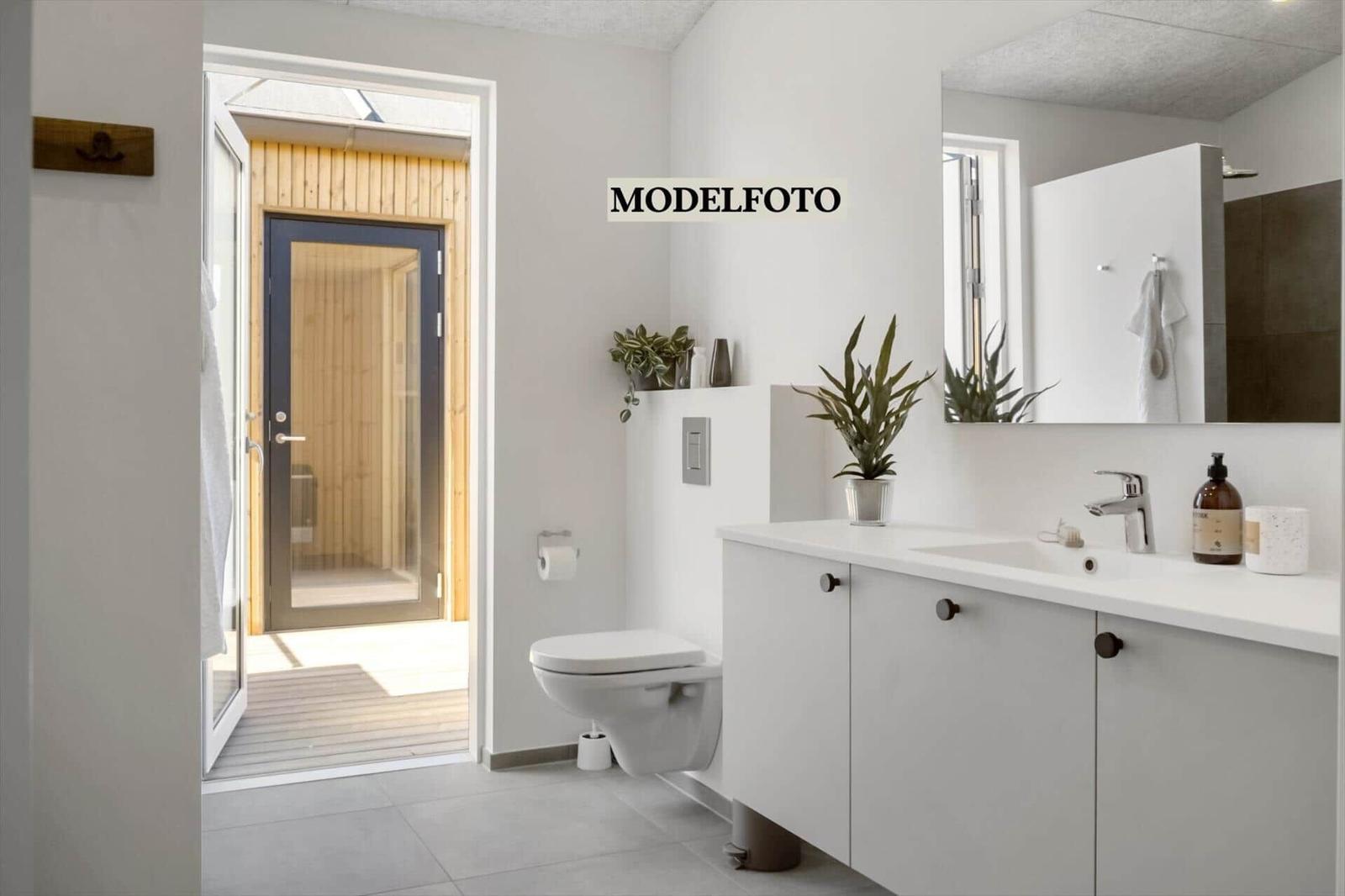 Badezimmer mit Waschbecken, Toilette und Tür zum Saunabereich.