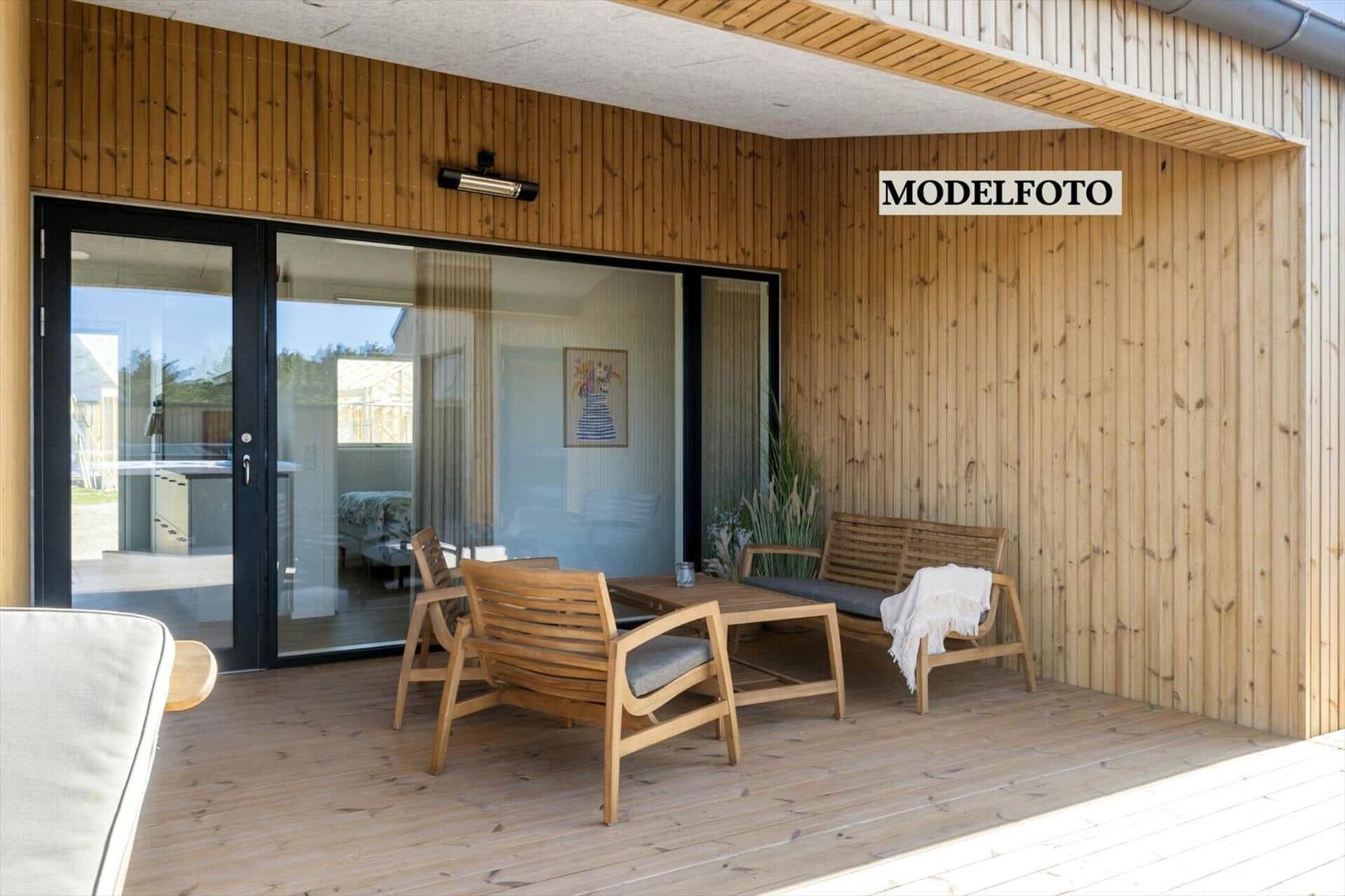 Terrasse mit Holzfußboden und Gartenmöbeln. Durchgang zur Inneneinrichtung.